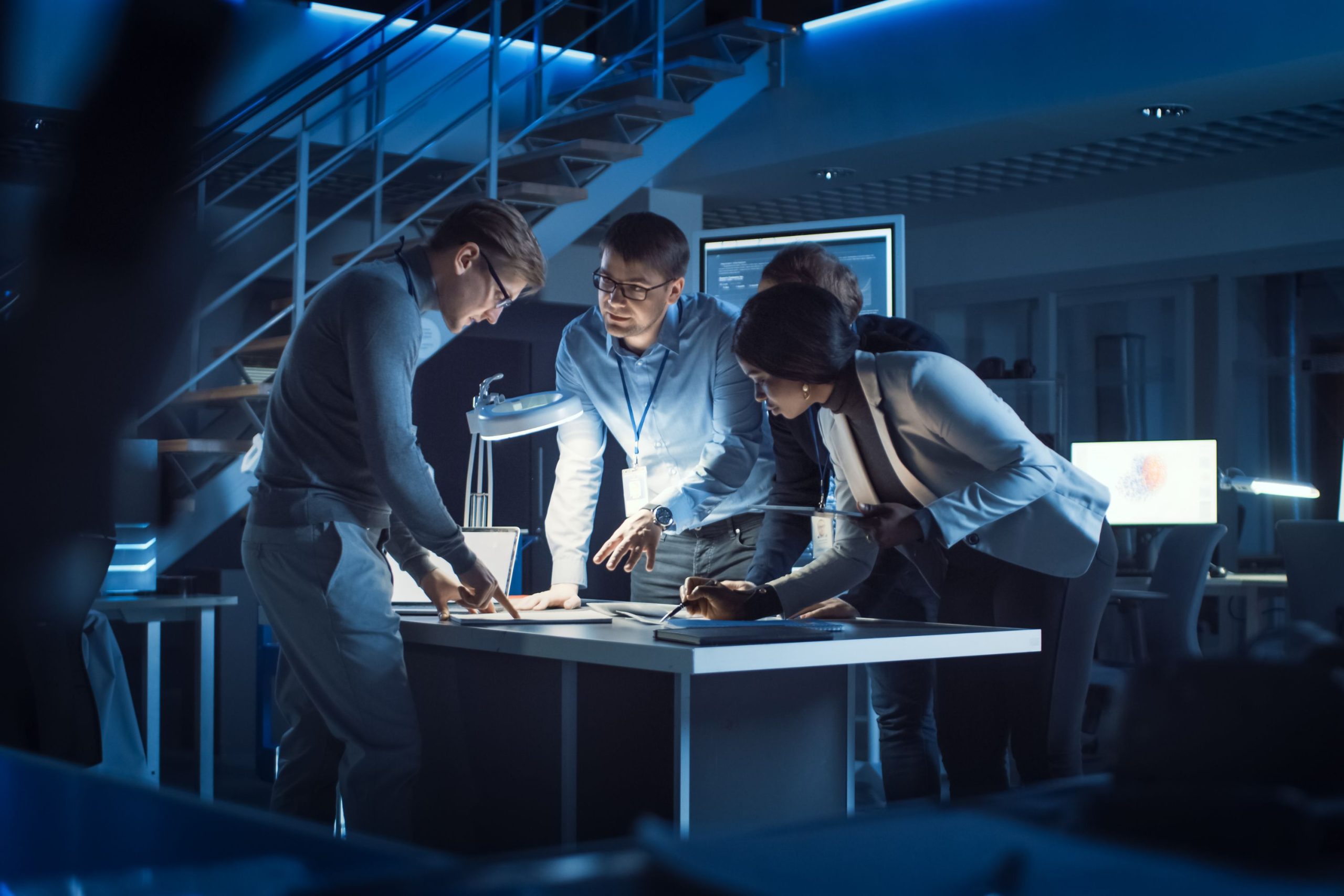 Zespół pracowników pracuje nad projektem w ciemnym laboratorium