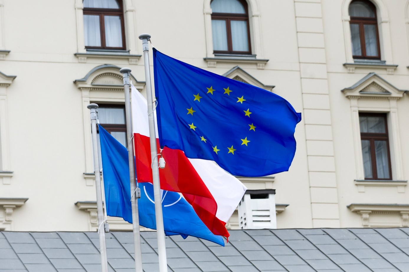 Zdjęcie przedstawia flagi na tle budynku, Fot. FOTOWAWA – Adobe Stock