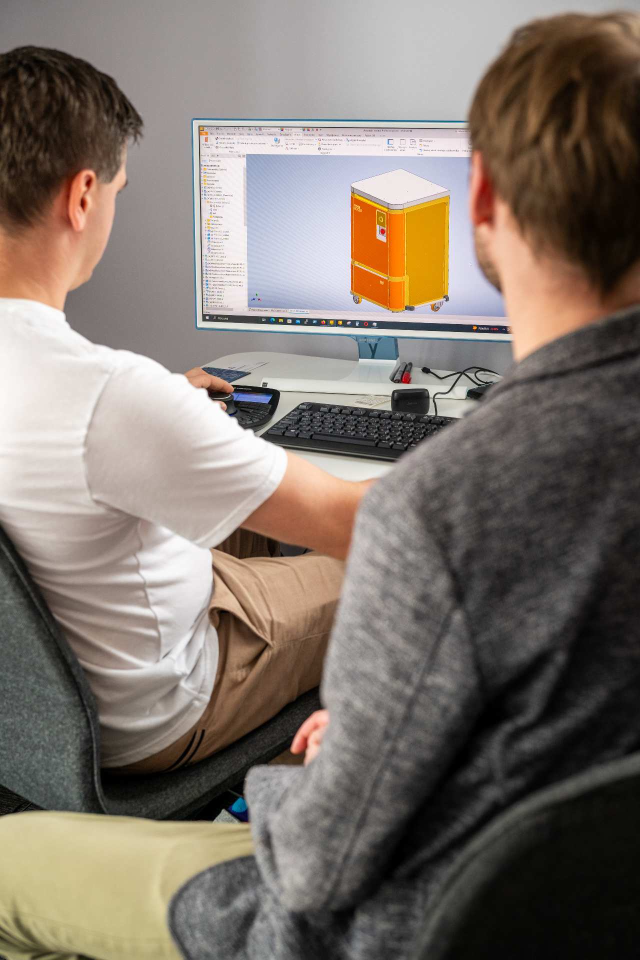 Dwóch młodych mężczyzn pracuje przy komputerze w programie graficznym.