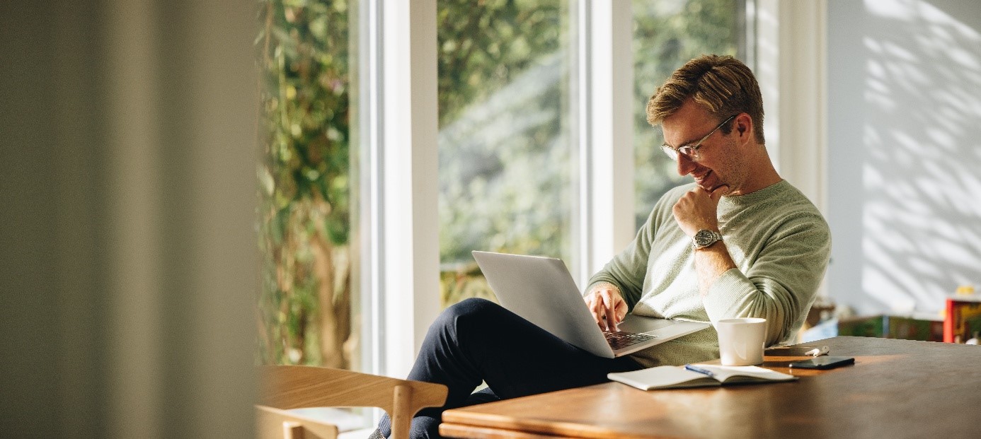 Uśmiechnięty mężczyzna przed lapotopem. Fot. Jacob Lund – Adobe Stock